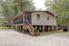 A two-story wooden cabin with a deck and a staircase leading to the upper level.
