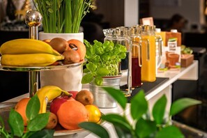 Eine Bar mit verschiedenen Früchten, einem Topfpflanzen und mehreren Getränkeflaschen.