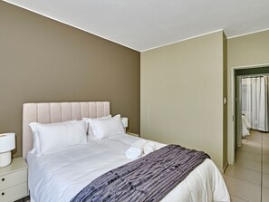 A hotel room with a bed, a nightstand, and a bathroom visible through an open door. - Regentis Executive Stays at The Atrium unit 151 (City of Johannesburg Metropolitan Municipality)