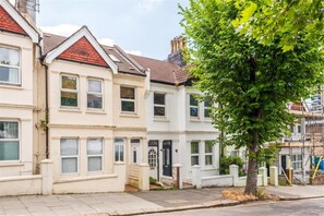 A row of terraced houses with a tree in the foreground. - Stylish 1BDR Hove Home with Private Patio (Brighton and Hove)