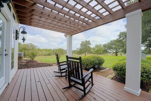 A wooden deck with two rocking chairs under a pergola, overlooking a grassy yard with trees. - Ranch Retreat Off Hwy 10 (Weimar)