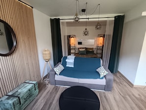 A modern bedroom with a bed, bedside lamps, a round floor lamp, and a wooden headboard. - Le Bicoquet in Caen: An Elegant and Cozy Apartment (Caen)