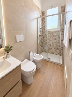 A modern bathroom with a shower, toilet, bidet, and sink. - LEVANTE PRIVÉ – Pool Retreat Salento (Lequile)