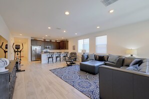 A spacious living area with a sofa, a dining table, and a kitchen in the background. - Pool & Hot Tub Access! Goodyear Extended Escape (Goodyear)