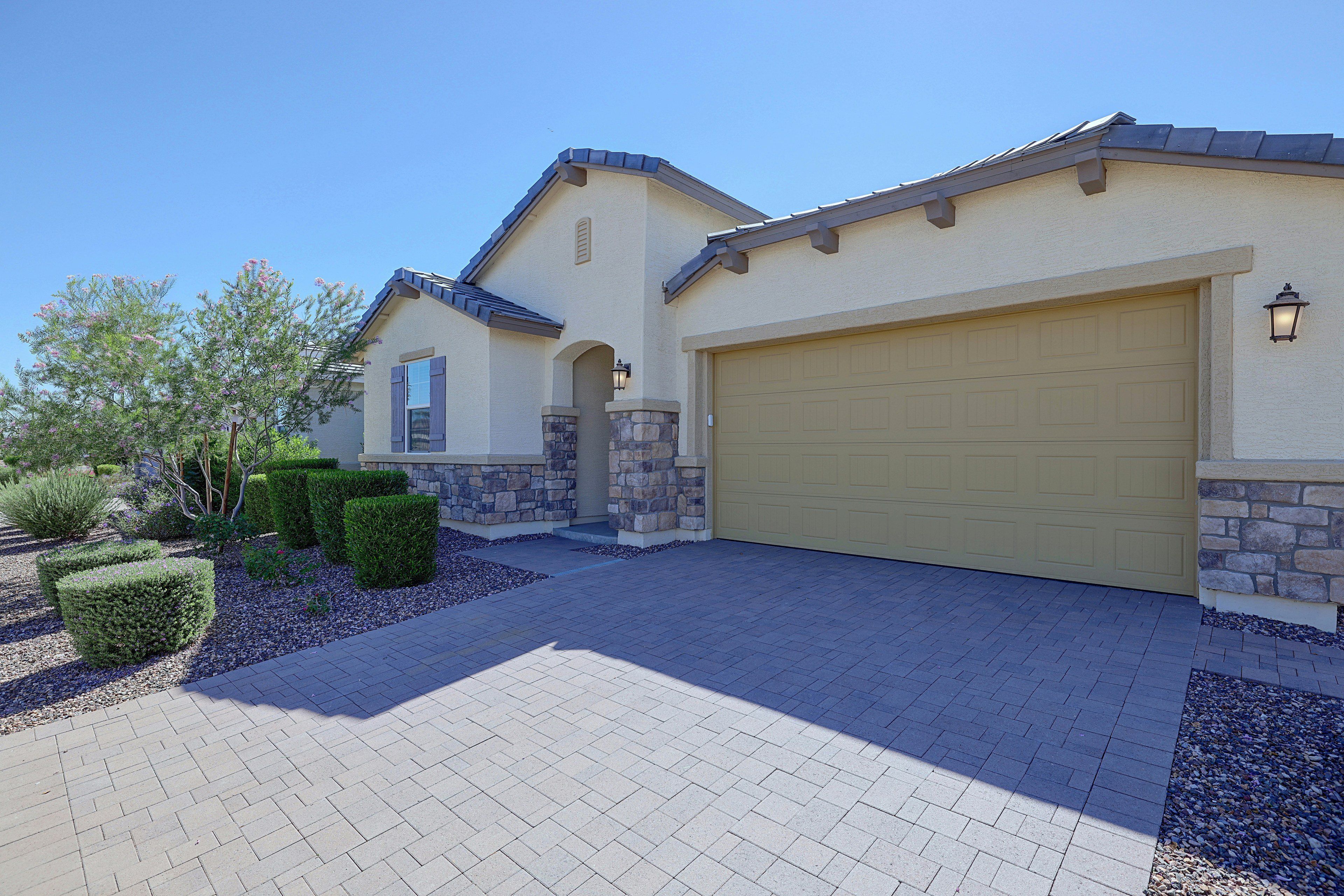 A two-story house with a garage, stone pillars, and a landscaped driveway.
