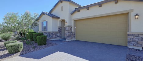 A two-story house with a garage, stone pillars, and a landscaped driveway.