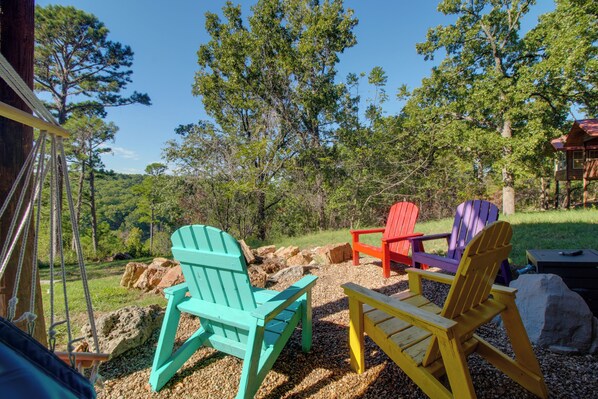 Outdoor seating with Adirondack chairs in various colors, surrounded by trees and a clear sky. - Grand Lake Escape: Deck, Hot Tub, Views! (Eucha)