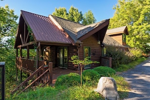 Eine Blockhütte mit Veranda, Treppe und einem kleinen Garten.