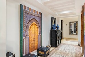 A hallway with a decorative archway, a black cabinet with blue vases, and a patterned rug. - Amazing apartment in the heart of Marrakesh (Marrakesh)