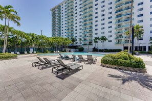 A hotel pool area with lounge chairs, a swimming pool, and a tall building in the background. - Resort Condo w/ Views in Sunny Isles Beach! (Sunny Isles Beach)