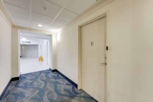 A hotel hallway with a carpeted floor, a door on the right, and a caution sign on the left. - Resort Condo w/ Views in Sunny Isles Beach! (Sunny Isles Beach)