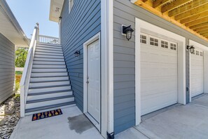A residential garage with a white door and a set of stairs leading up to the entrance. - Ocean Isle Group Stay w/ 3 Private Units (Ocean Isle Beach)