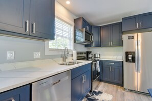 A modern kitchen with dark blue cabinets, stainless steel appliances, and a white countertop. - Ocean Isle Group Stay w/ 3 Private Units (Ocean Isle Beach)