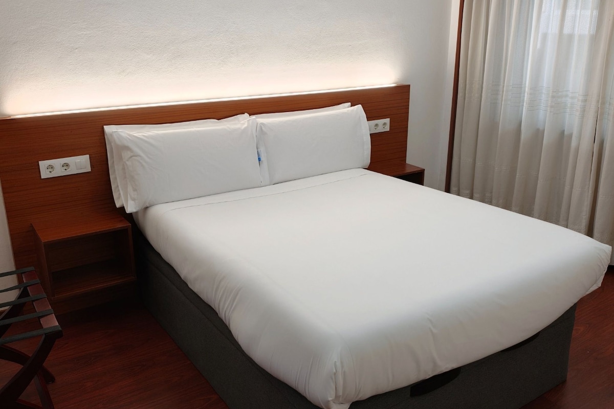 A hotel room with a bed, nightstands, and a wooden headboard.