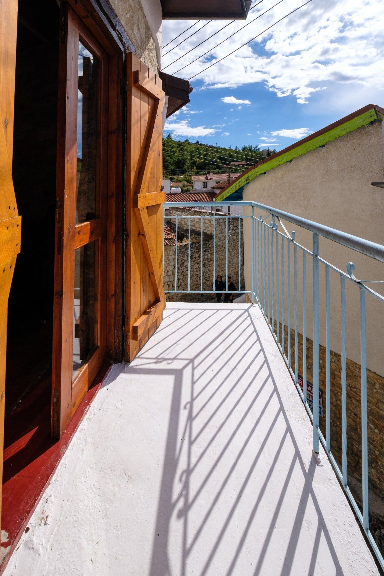 A balcony with a wooden door, a metal railing, and a view of a residential area.