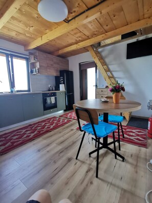 Una cocina moderna con vigas de madera, una mesa de comedor con sillas y un tapete estampado rojo.