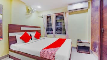 A hotel room with a bed, a nightstand, an air conditioning unit, and a wardrobe.