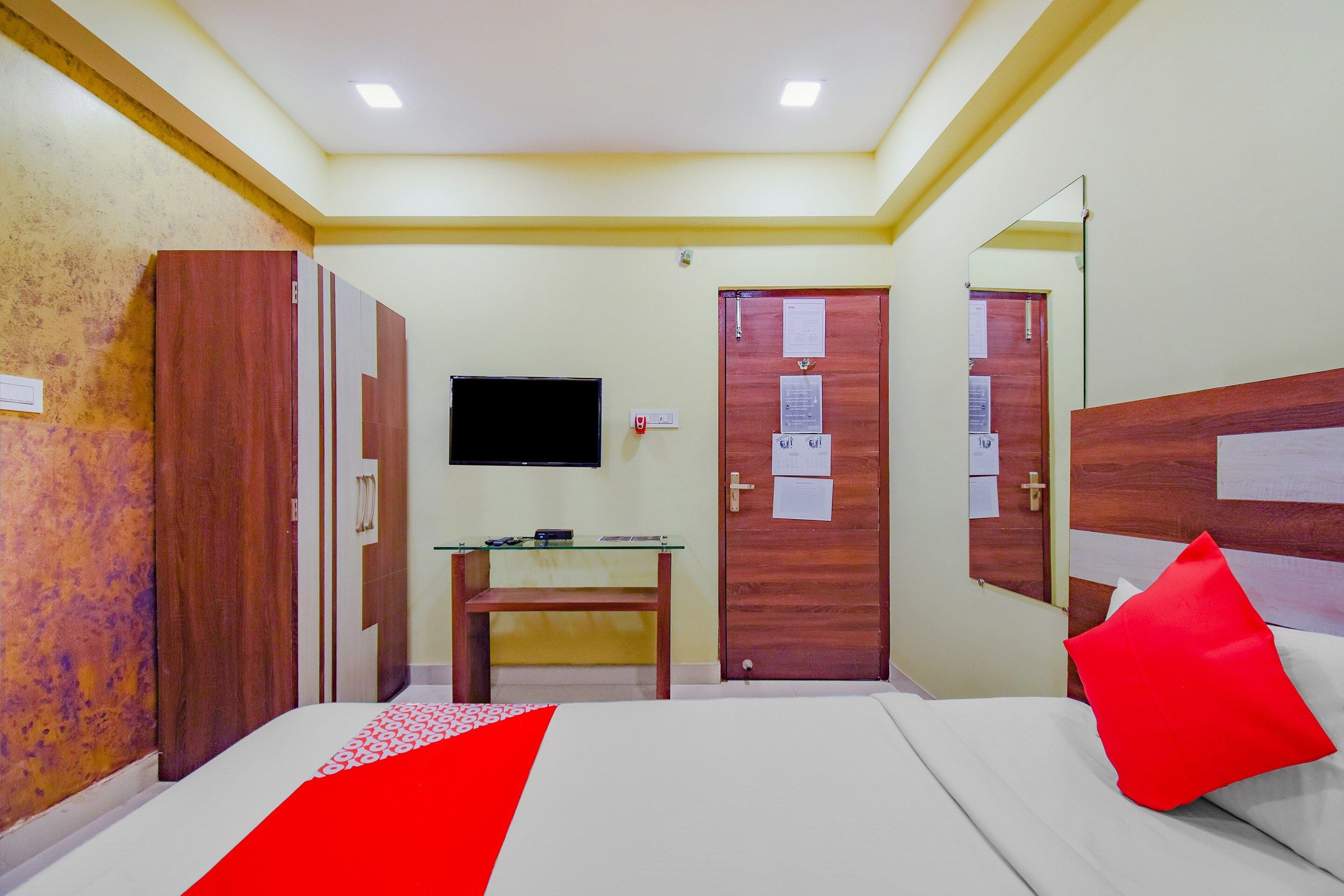 Una habitación de hotel con cama, escritorio, televisor y dos puertas.