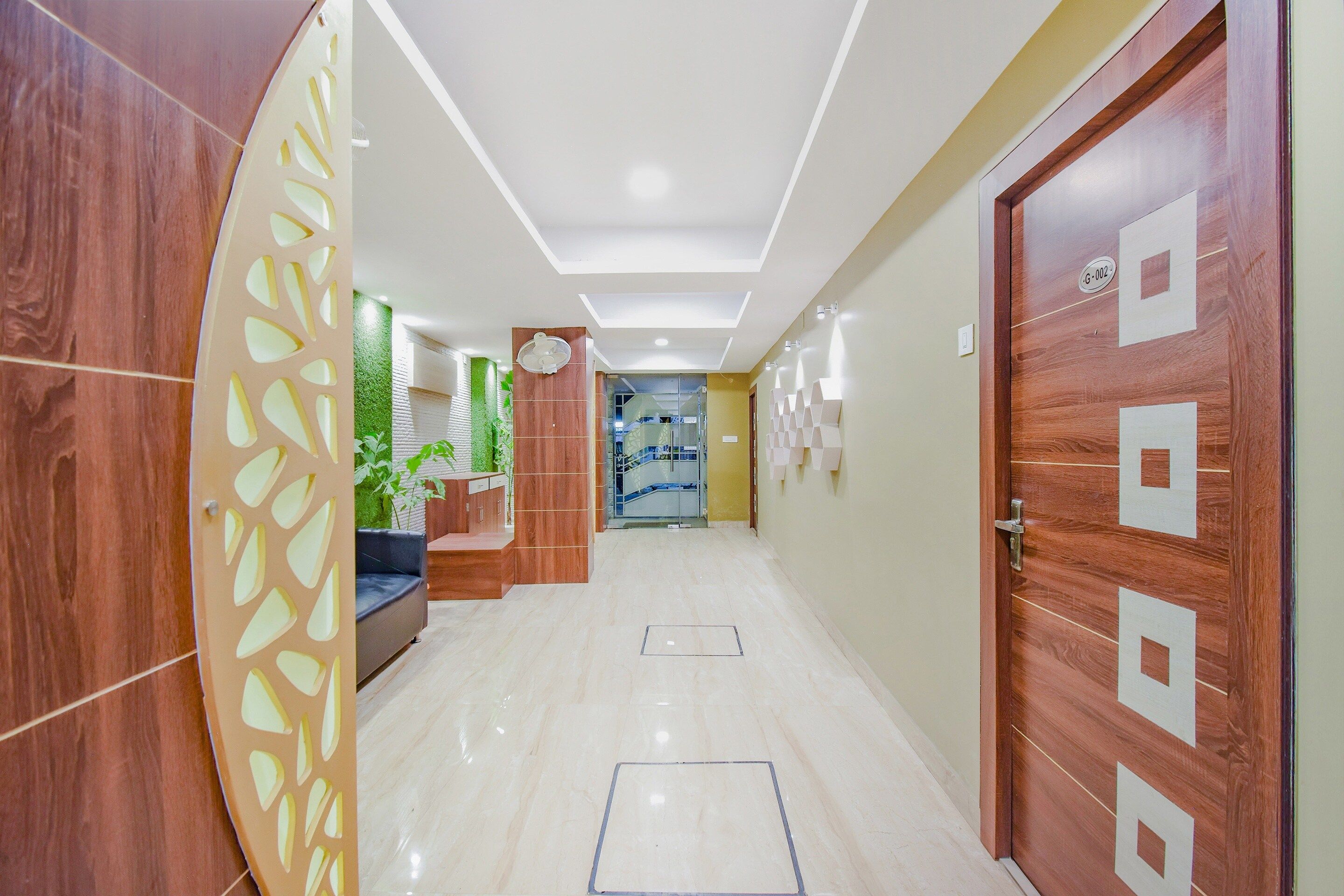 A hallway with a wooden door, a reception desk, and a plant.