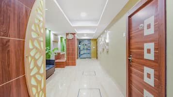A hallway with a wooden door, a reception desk, and a plant.