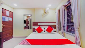 Una habitación de hotel con cama, espejo, ventana con cortinas y puerta.