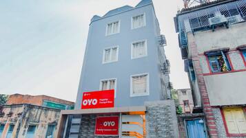 Un edificio de varios pisos con un llamativo letrero rojo de OYO, que indica un hotel o alojamiento.