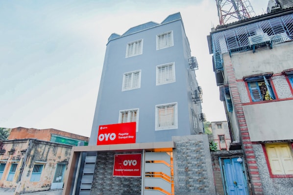 Um edifício de vários andares com uma placa vermelha chamativa da OYO, indicando um hotel ou acomodação.