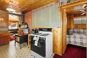 A compact kitchen with a gas stove, a coffee maker, and a brick wall. - 1 Mi to Bear Mtn Lifts! Moonridge Alpine Cabin (Big Bear Lake)