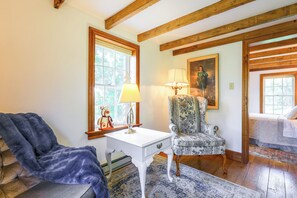 A room with a white table, a patterned armchair, a blue chair, a lamp, and a painting on the wall. - Peaceful Farm House Near Catoctin Mtn Park (Myersville)