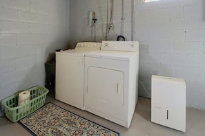 A laundry room with a large washer and dryer, a green laundry basket, and a patterned rug. - Game Room & Foosball! Fayetteville Family Home (Fayetteville)