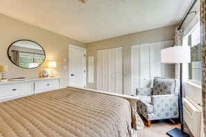 A bedroom with a large bed, a bedside table, a lamp, a chair, and a wardrobe. - 10 Mi to Gunstock Resort! Condo Near Lake Access (Laconia)