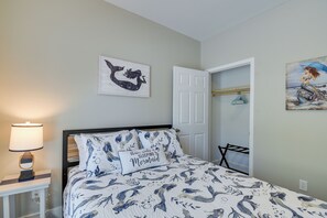 Ein Schlafzimmer mit Bett, Nachttisch, Lampe, Tür und Kleiderschrank.