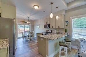 A modern kitchen with a large island, stainless steel refrigerator, and pendant lighting. - 2-Unit Ocean Isle Beach Getaway Near Pier & Dining (Ocean Isle Beach)