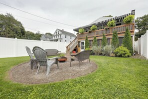 A backyard with a patio area, two chairs, a fire pit, and a white fence. - Comfy & Cozy Home Close to Penn State! (Pleasant Gap)
