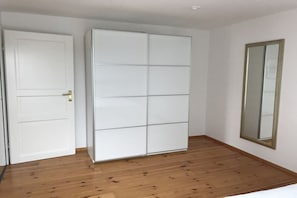 Ein Zimmer mit einem weißen Kleiderschrank, einer Tür und einem Spiegel an der Wand.