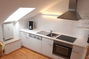 A compact kitchen with a dishwasher, oven, and a coffee maker. - Holiday apartment with 1 bedroom (Stegaurach)