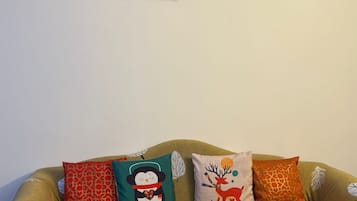 A sofa with a leaf pattern, a framed picture on the wall, and three decorative pillows.