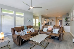 A modern living room with a brown leather sofa, a white coffee table, and a ceiling fan. - Steps to Sylvan Beach Park! Family Getaway (La Porte)