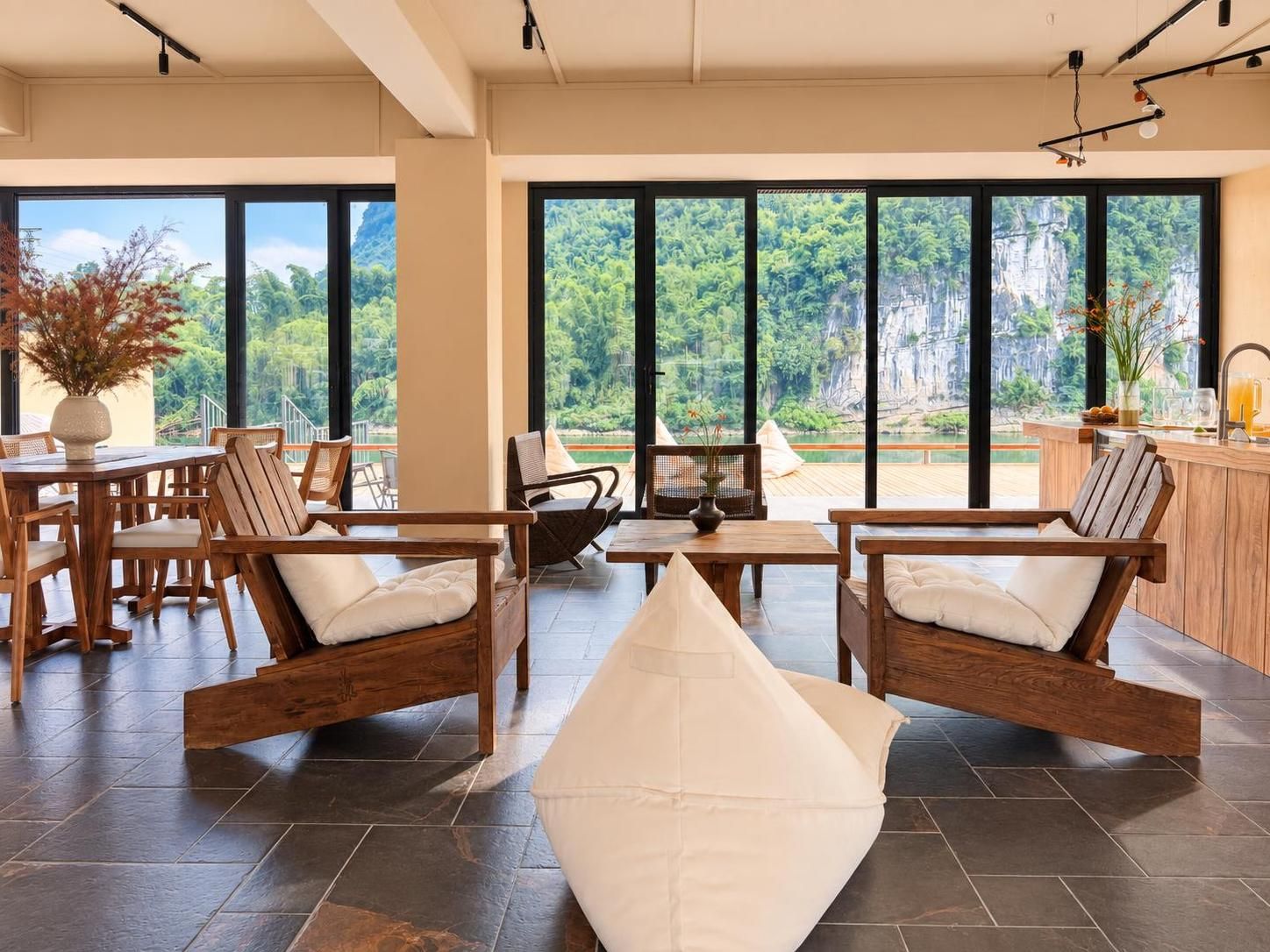 A spacious room with large windows, wooden furniture, and a view of a natural landscape.