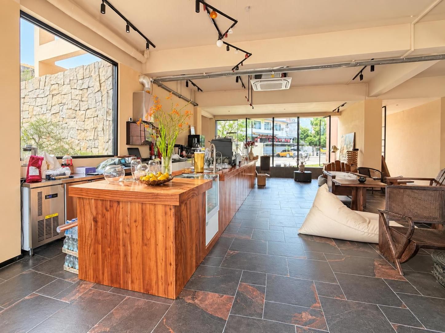 Una cocina moderna con una isla central de madera, una pared de piedra y vistas a la calle.