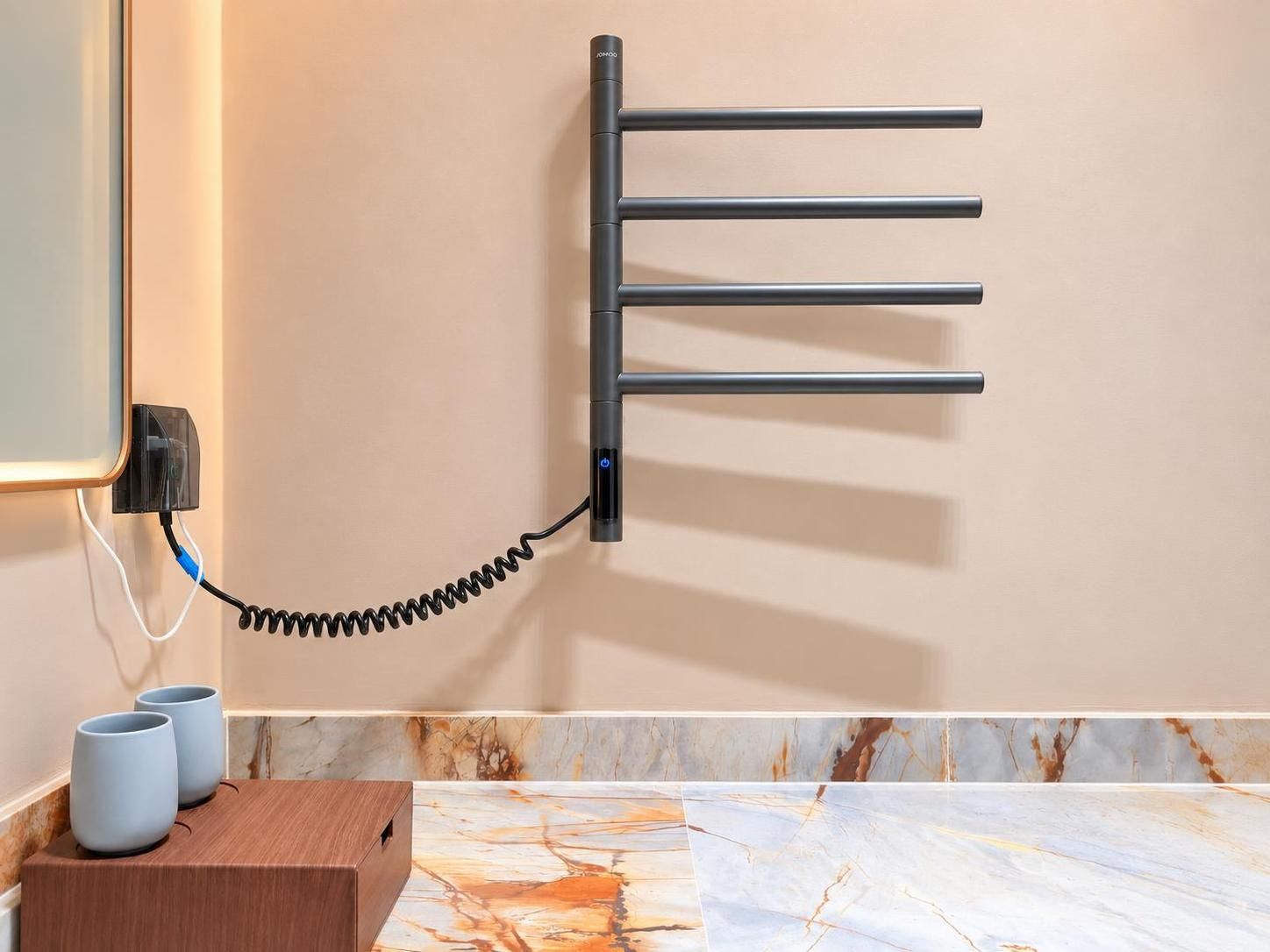 Un perchero de pared con un cable enrollado, un enchufe y dos tazas sobre una superficie de madera.