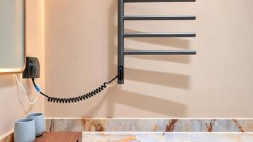 Un perchero de pared con un cable enrollado, un enchufe y dos tazas sobre una superficie de madera.