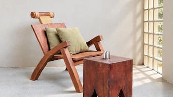 A wooden chair with a cushion and a metal table in a room with a window.