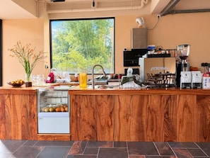 A modern kitchen with a wooden counter, a coffee machine, and a view of greenery outside. - TMAN RESORT (Guilin)