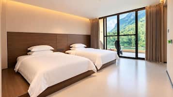 A hotel room with two beds, a large window with a mountain view, and a modern design.