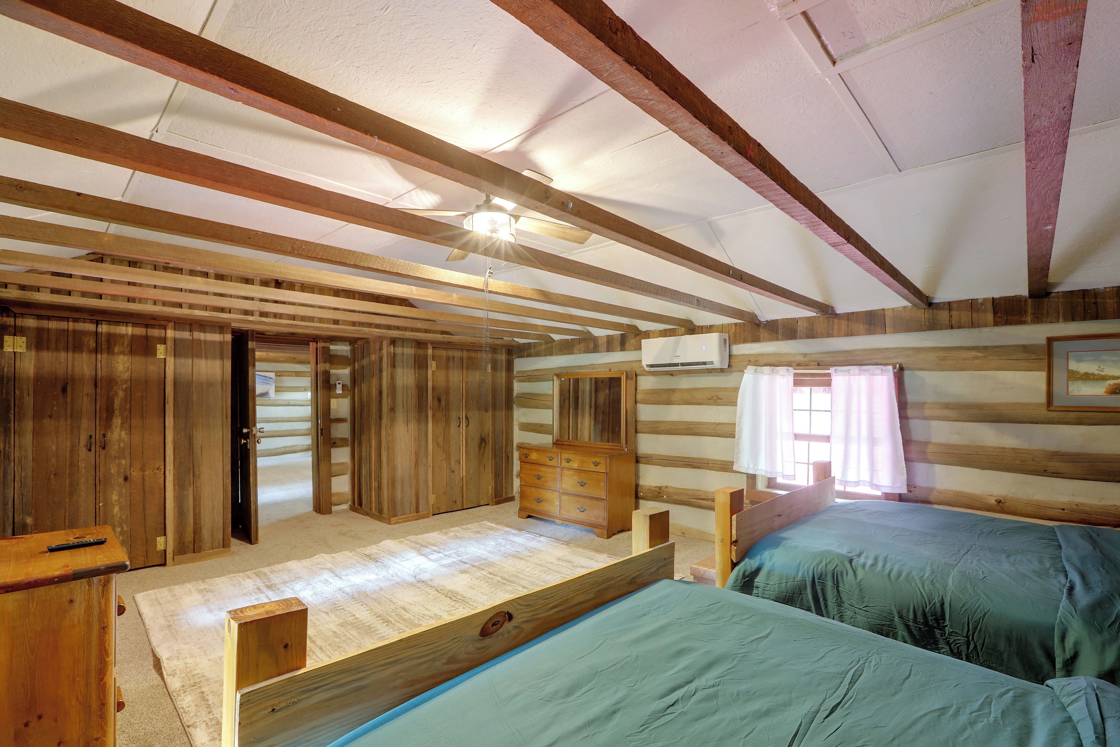 A cabin with a loft bed, a wooden wardrobe, and a ceiling fan.