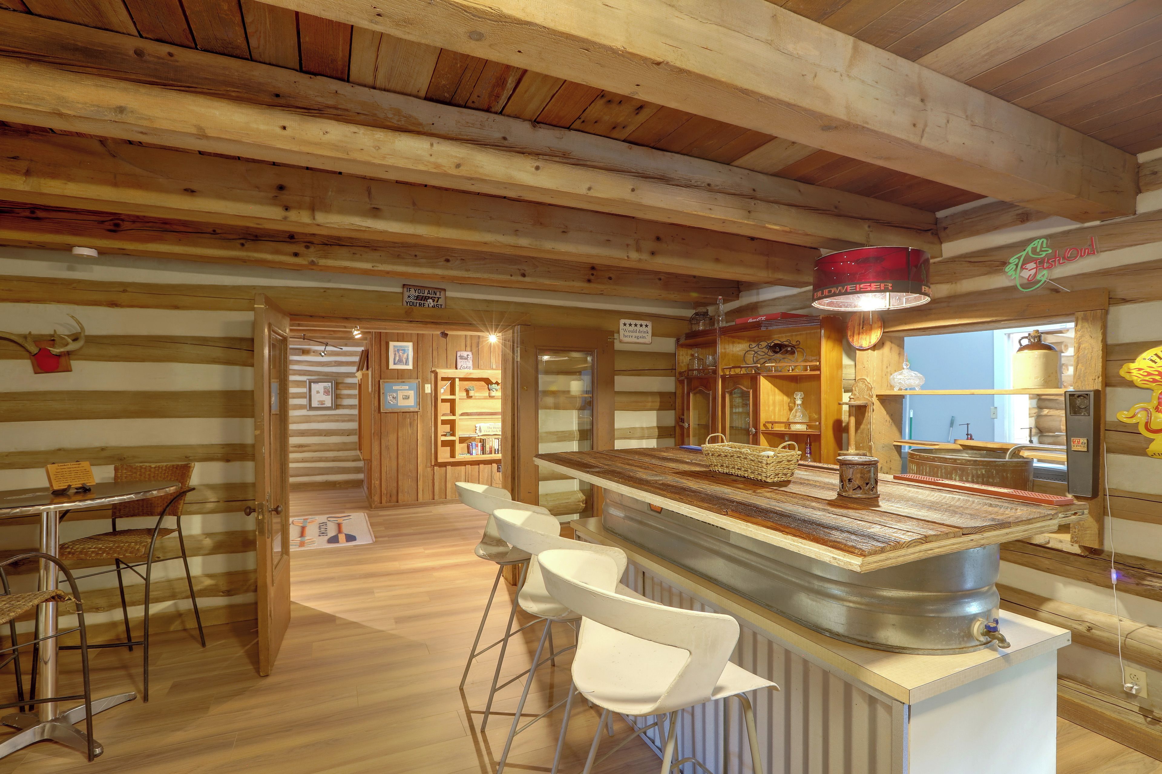 A rustic wooden interior with a bar area, bar stools, and a wooden ceiling.