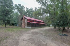 A rustic cabin with a red roof, surrounded by trees and a dirt path. - Across From Marina! Lake Seminole Fishing Lodge (Bainbridge)
