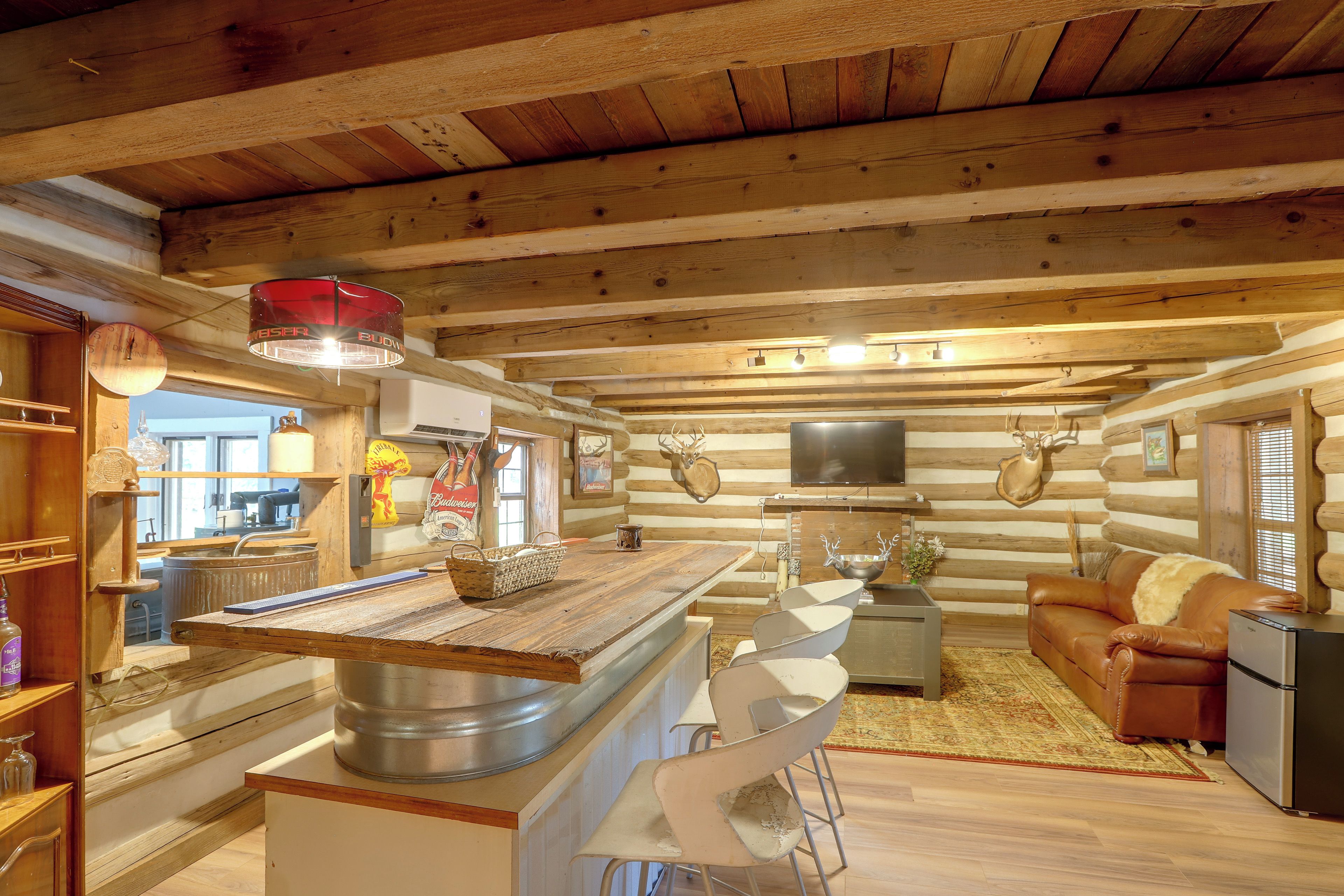 L’intérieur d’une cabane en rondins, avec un îlot central, un canapé et un téléviseur.