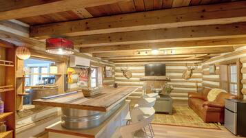 Ein Holzblockhaus-Interieur mit einer zentralen Kücheninsel, einem Sofa und einem Fernseher.